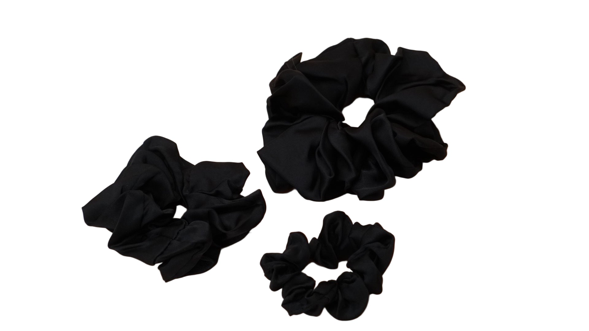 Three black scrunchies on a white background