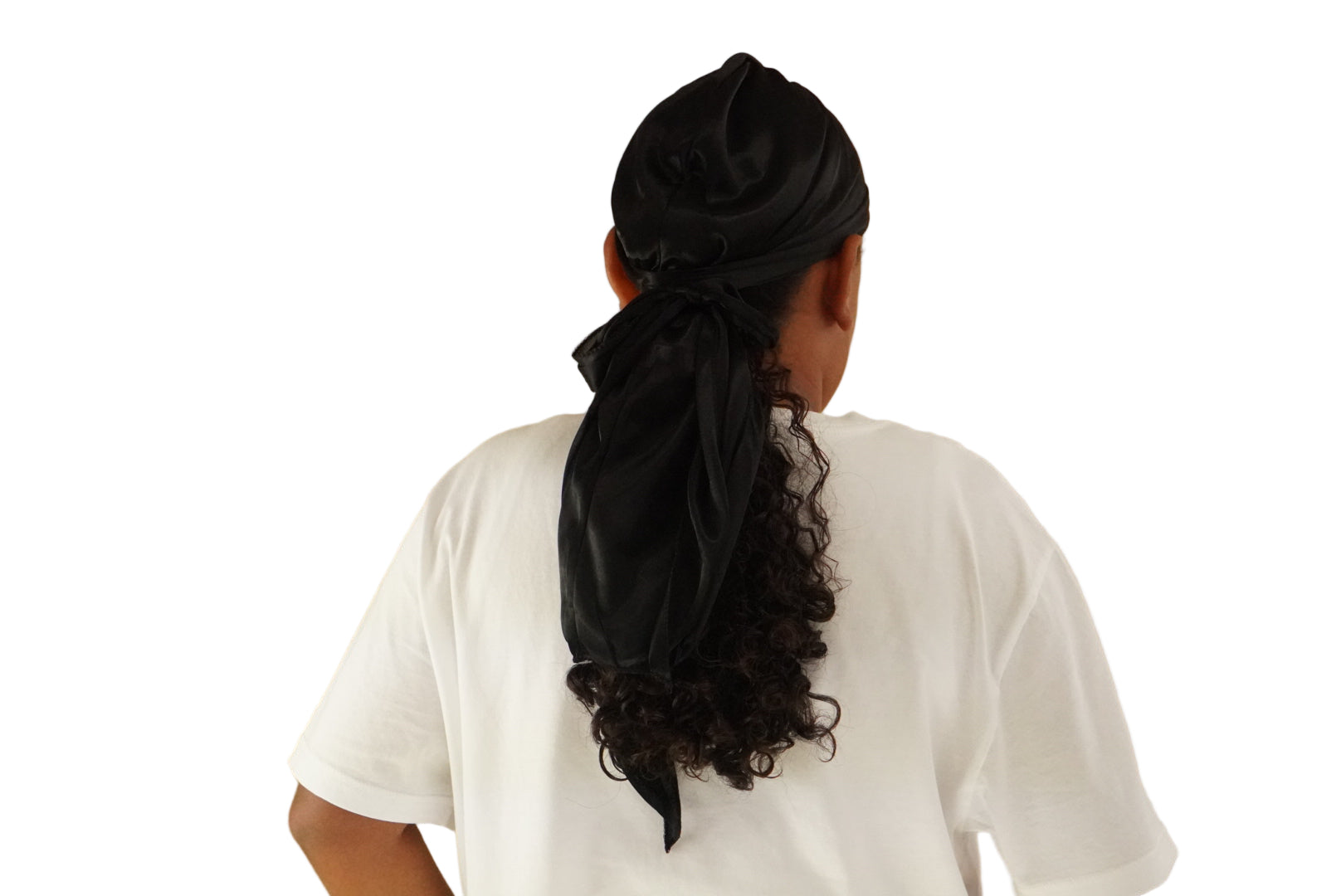 Person wearing a black headscarf with a ponytail on a beige background