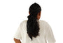 Person wearing a black headscarf with a ponytail on a beige background