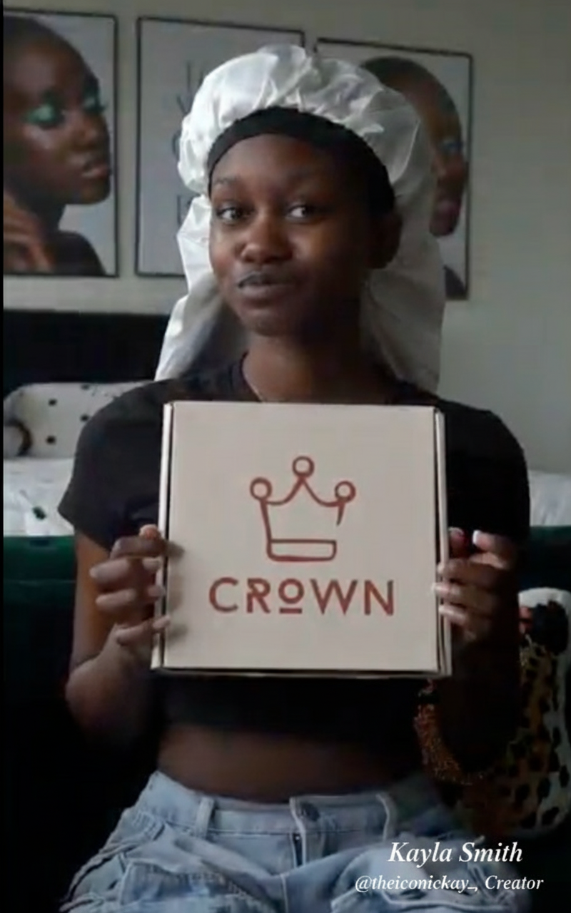 Person holding a sign with 'CROWN' and a crown logo indoors.